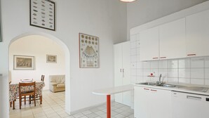 A modern kitchen with white cabinets, a built-in dishwasher, and a dining area with a floral tablecloth. - Agriturismo Campo al Crognolo. (Sassofortino)