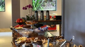 En buffé med ett varierat utbud av mat och en kaffestation, placerad under hängande lampor med trädetaljer.