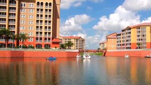 Un hotel frente al agua con varias construcciones, una masa de agua tranquila y varias embarcaciones.