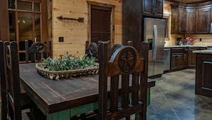 A wooden interior with a dining table, chairs, and a refrigerator.