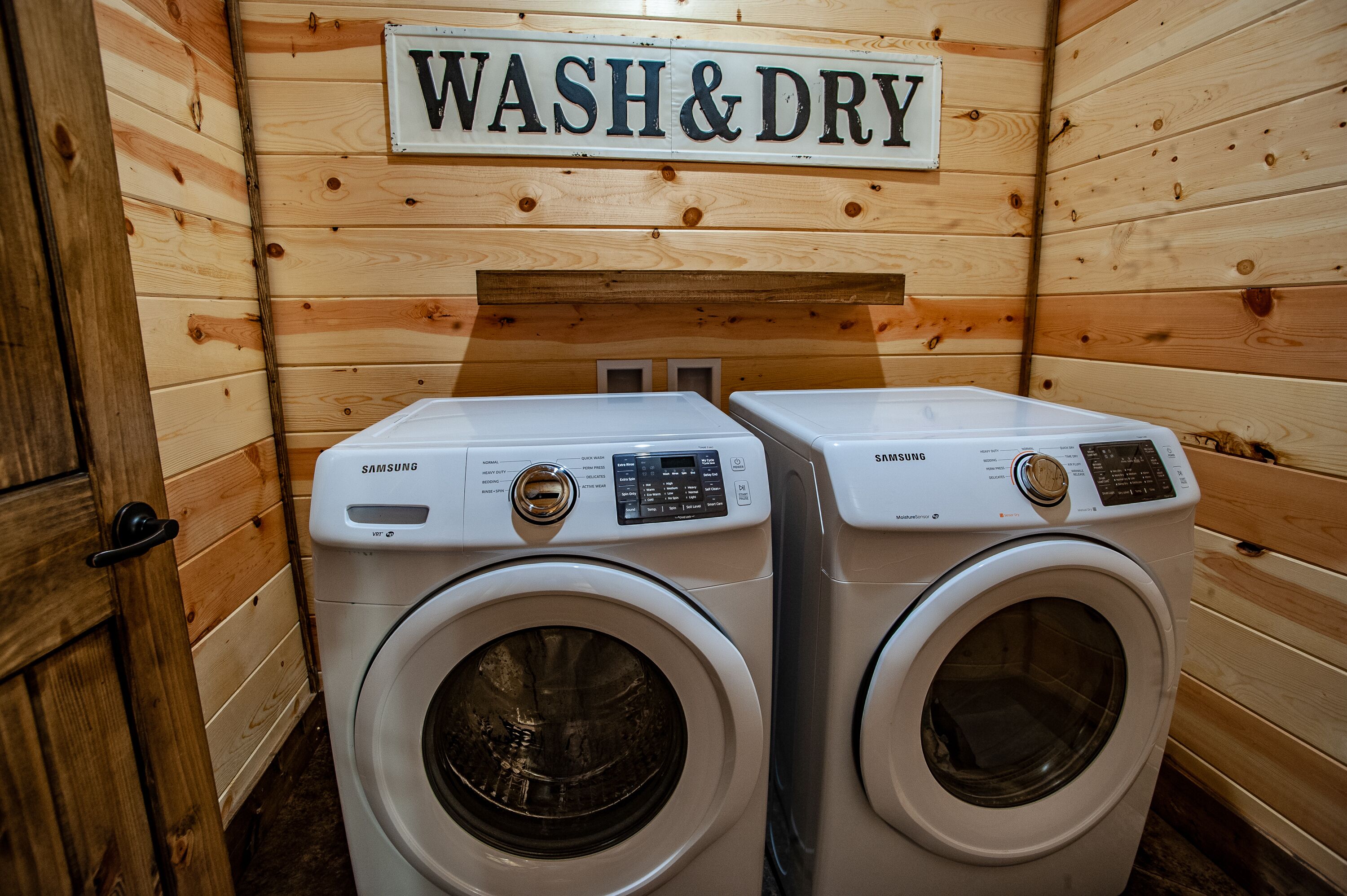 Un lavadero con dos lavadoras Samsung y un letrero que dice 'WASH & DRY'.