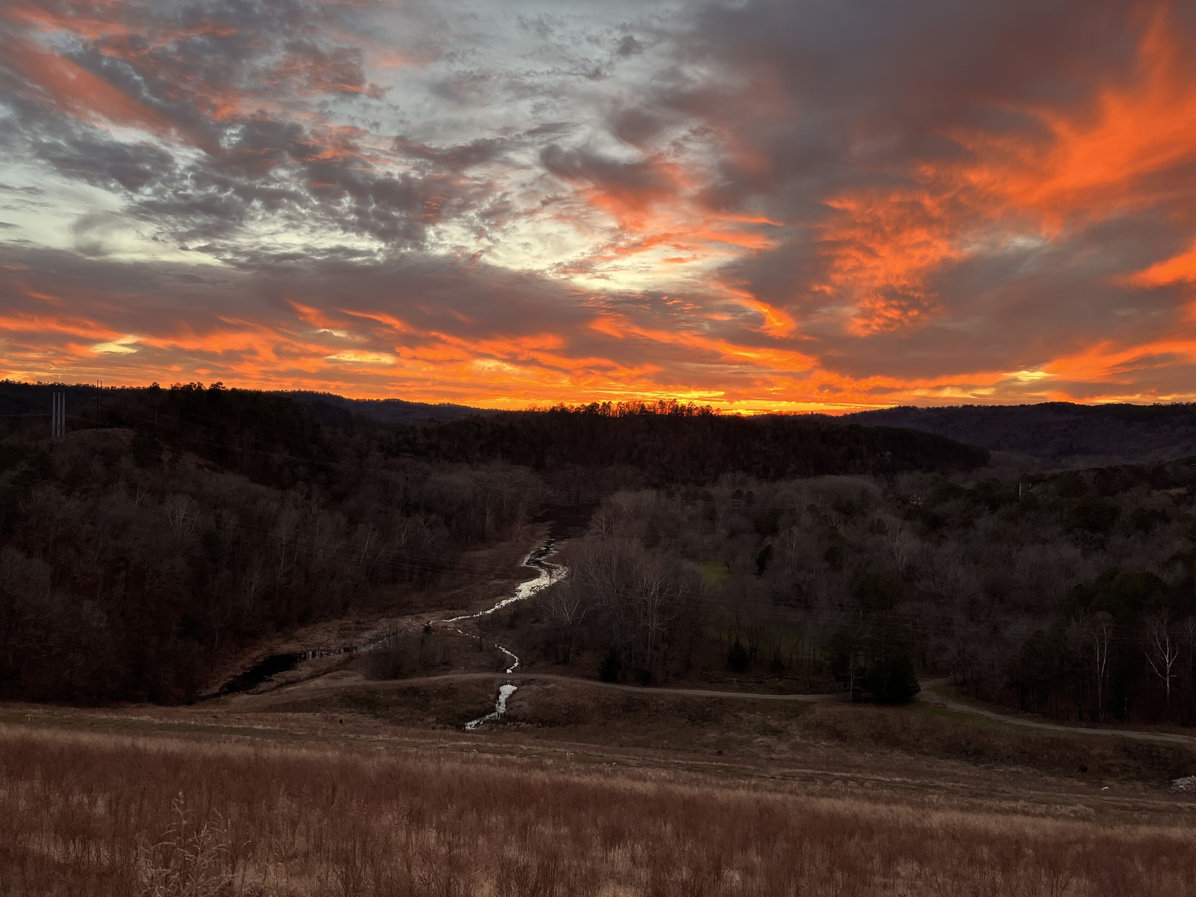 A river winding through a forested valley with a dramatic sunset sky.