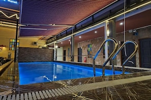 An indoor swimming pool with a marble floor, metal railings, and a ceiling with linear lighting. - Banana Boutique Hotel (George Town)