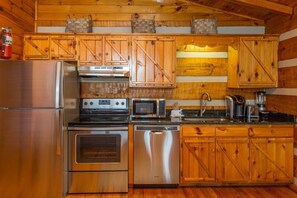 Una cocina con armarios de madera, electrodomésticos de acero inoxidable y un extintor.