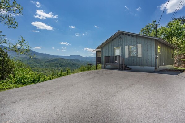 A single-story building with a porch, a clear sky, and a mountainous landscape in the background.
