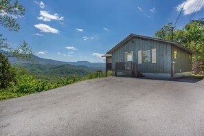 A single-story building with a porch, a clear sky, and a mountainous landscape in the background.