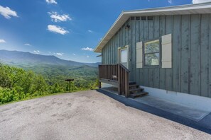 Una cabaña de madera con un porche y vistas a las montañas.