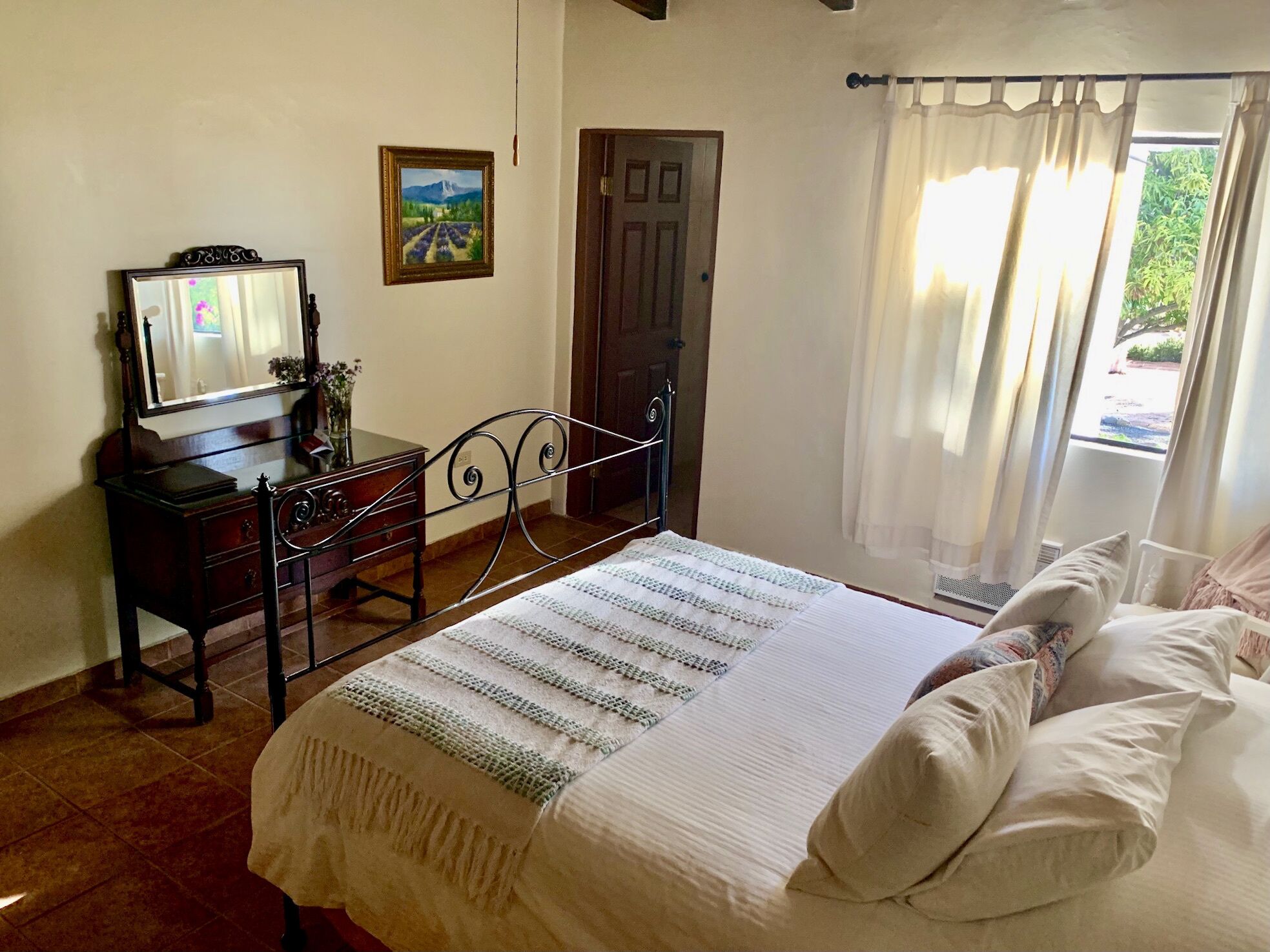 A bedroom with a bed, a dresser, a mirror, and a door.