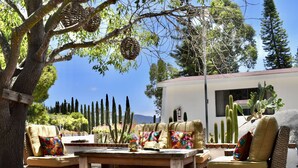 An outdoor seating area with wicker furniture, a wooden table, and a cactus garden. - Rancho el Parral in Valle de Guadalupe Surrounded by nature (Ensenada)