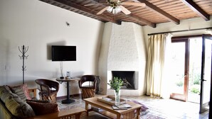 A living room with a fireplace, a television, and a ceiling fan. - Rancho el Parral in Valle de Guadalupe Surrounded by nature (Ensenada)