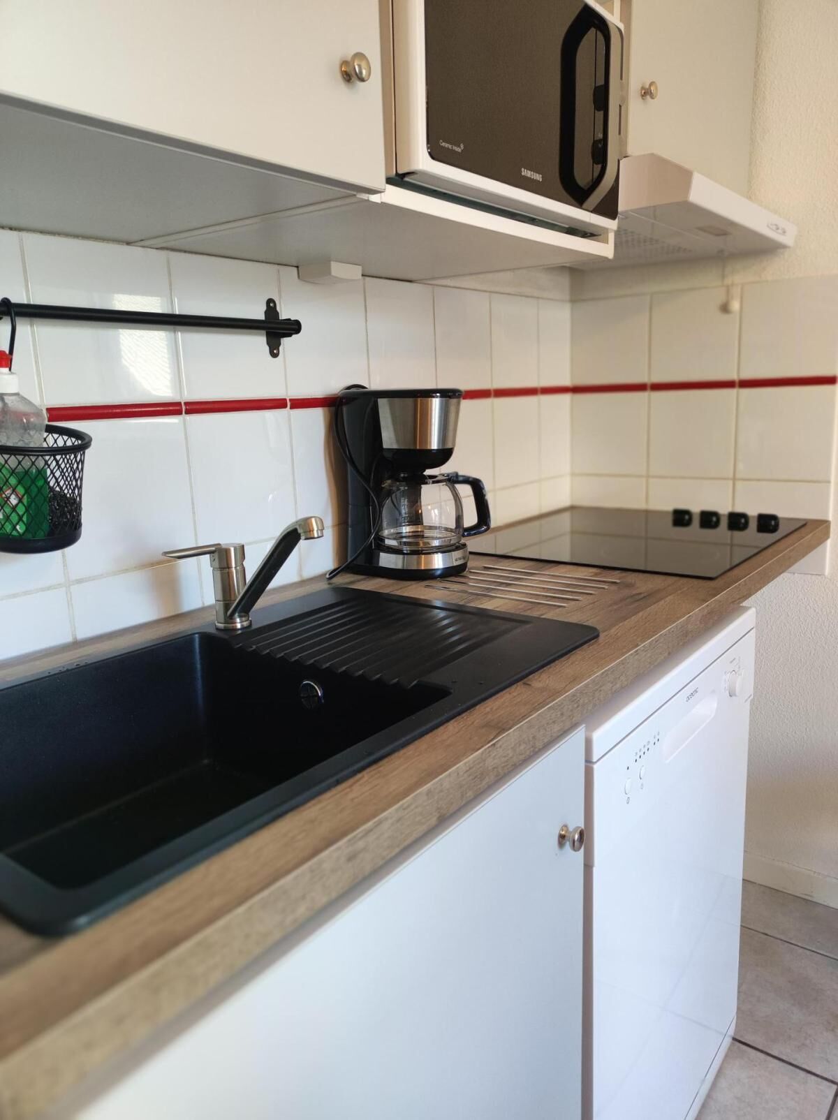 A kitchen with a black sink, a coffee maker, and a microwave above the counter.
