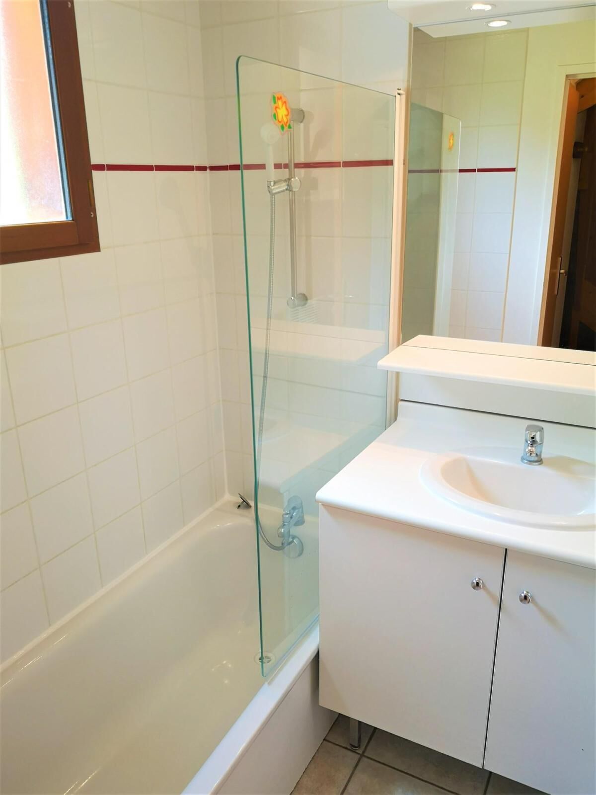 A modern bathroom with a glass-enclosed shower, a white sink, and a mirror above the vanity.