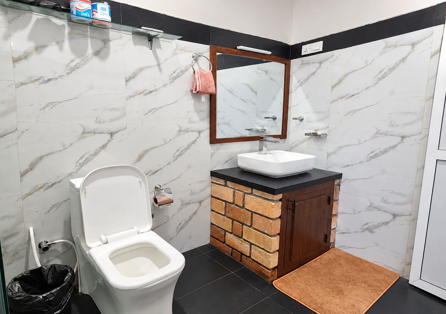 A bathroom with a white toilet, a sink with a black countertop, and a mirror above the sink.
