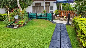 Um jardim bem cuidado com um caminho pavimentado que leva a uma área de estar coberta.