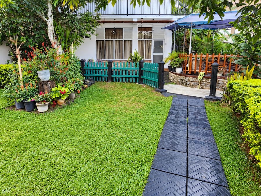 Un jardín bien cuidado con un sendero pavimentado que lleva a una zona de estar cubierta.
