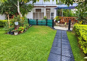 Un jardin bien entretenu, avec un chemin pavé menant à un espace de repos abrité.