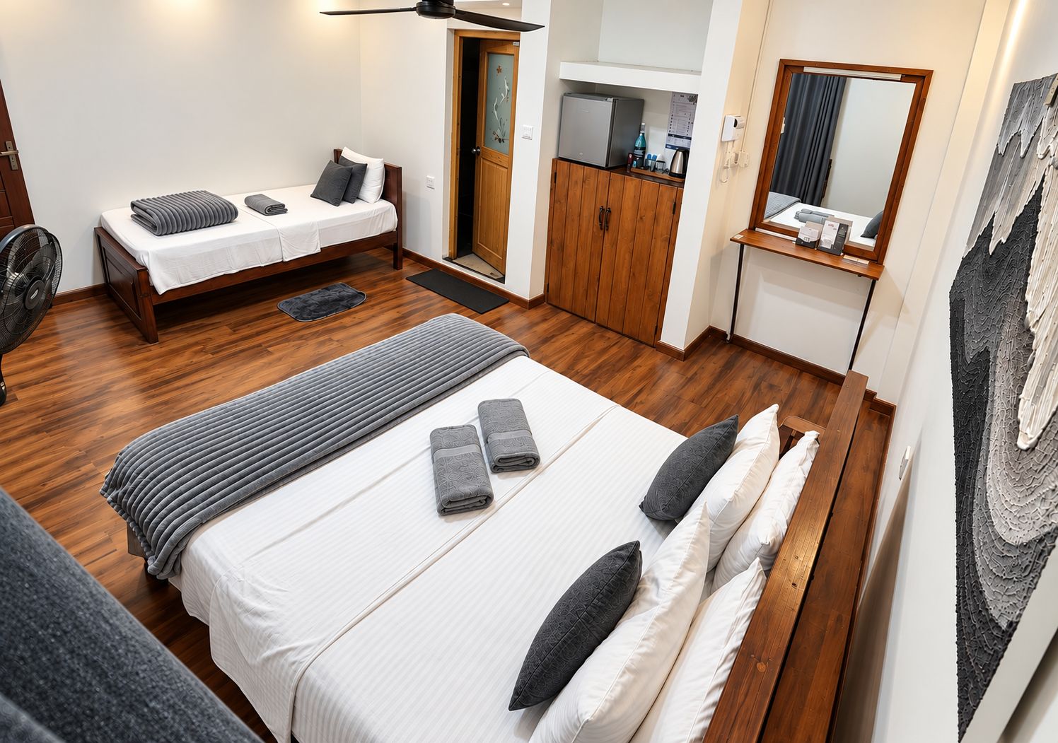 Een hotelkamer met een bed, bureau, garderobe en spiegel.