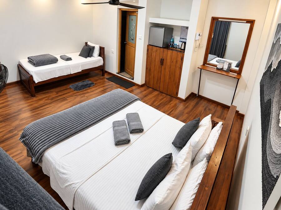 Una habitación de hotel con cama, escritorio, armario y espejo.