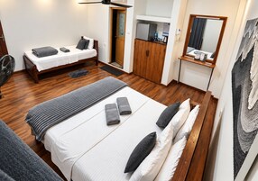 Una habitación de hotel con cama, escritorio, armario y espejo.