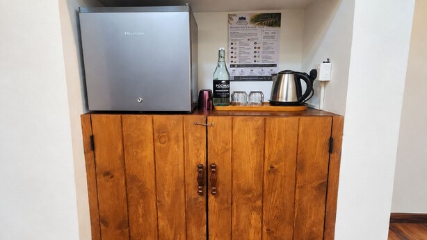 Un mueble de madera con un electrodoméstico de acero inoxidable encima, una botella y una tetera en la encimera.