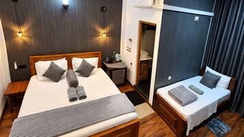 Habitación de hotel con una cama grande, una cama más pequeña, un escritorio, un armario y un ventilador de techo.