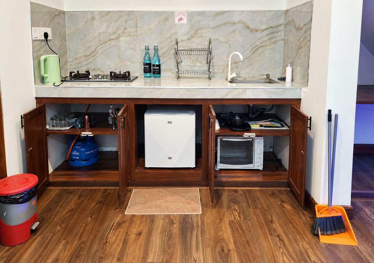 A compact kitchen with a built-in microwave, a small refrigerator, and a sink.
