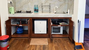 A compact kitchen with a built-in microwave, a small refrigerator, and a sink.