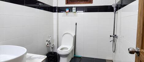 Een badkamer met toilet, hygiëneschuimer en douche.