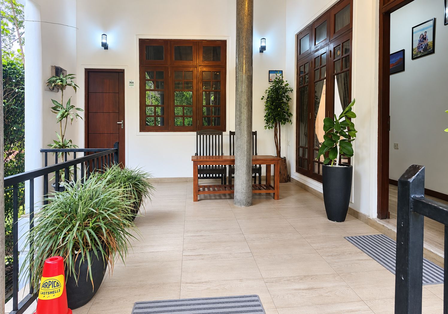 Um corredor espaçoso com um banco de madeira, plantas em vasos e uma grande janela com vista para o verde.