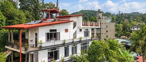 A multi-story building with balconies, surrounded by lush greenery.