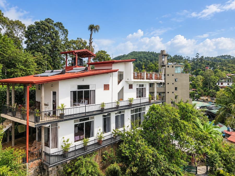 A multi-story building with balconies, surrounded by lush greenery.