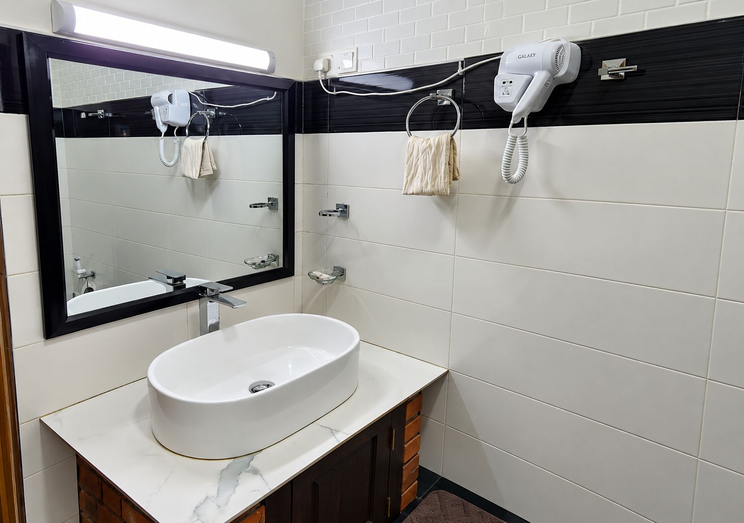 A bathroom with a white sink, a mirror, a hairdryer, and a towel rack.