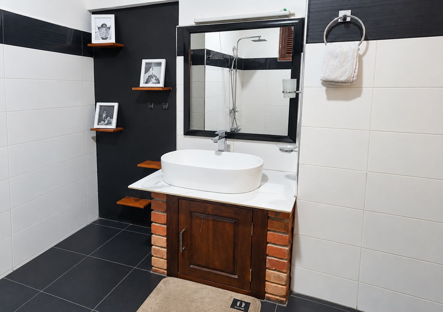 Een badkamer met een wit wastafelmeubel, een spiegel, een douche en een handdoekhouder.