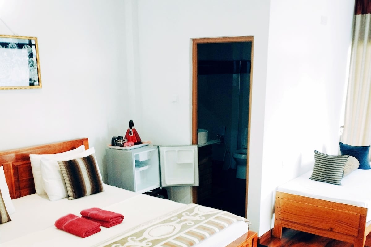 Une chambre d’hôtel avec un lit en bois, un petit bureau et une table de chevet.