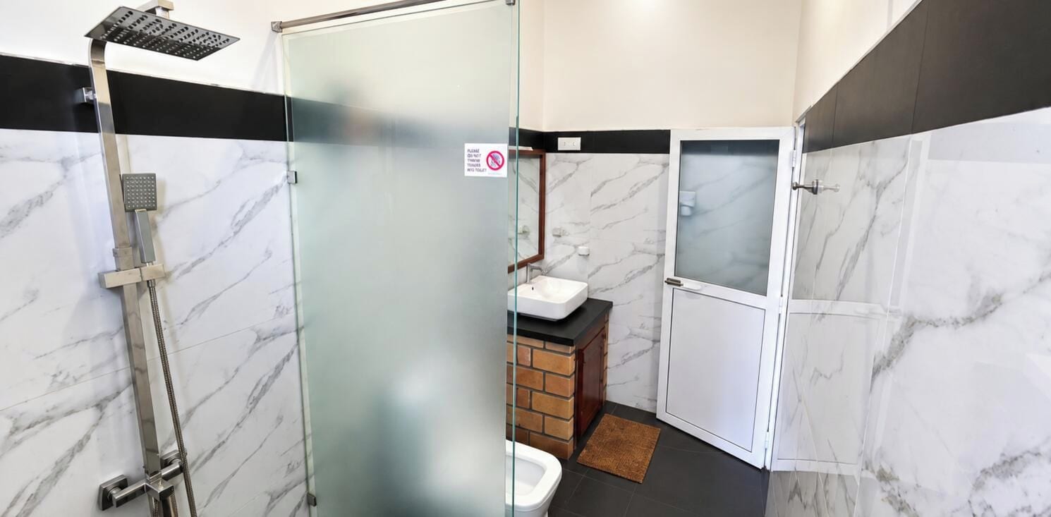Baño con cabina de ducha de vidrio, lavabo e inodoro.