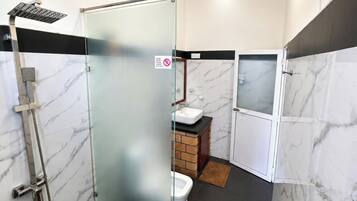 Baño con cabina de ducha de vidrio, lavabo e inodoro.