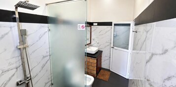 Baño con cabina de ducha de vidrio, lavabo e inodoro.