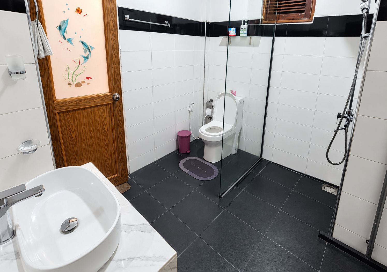Ein modernes Badezimmer mit einer Duschkabine aus Glas, einer weißen Toilette und einem Marmorwaschbecken.
