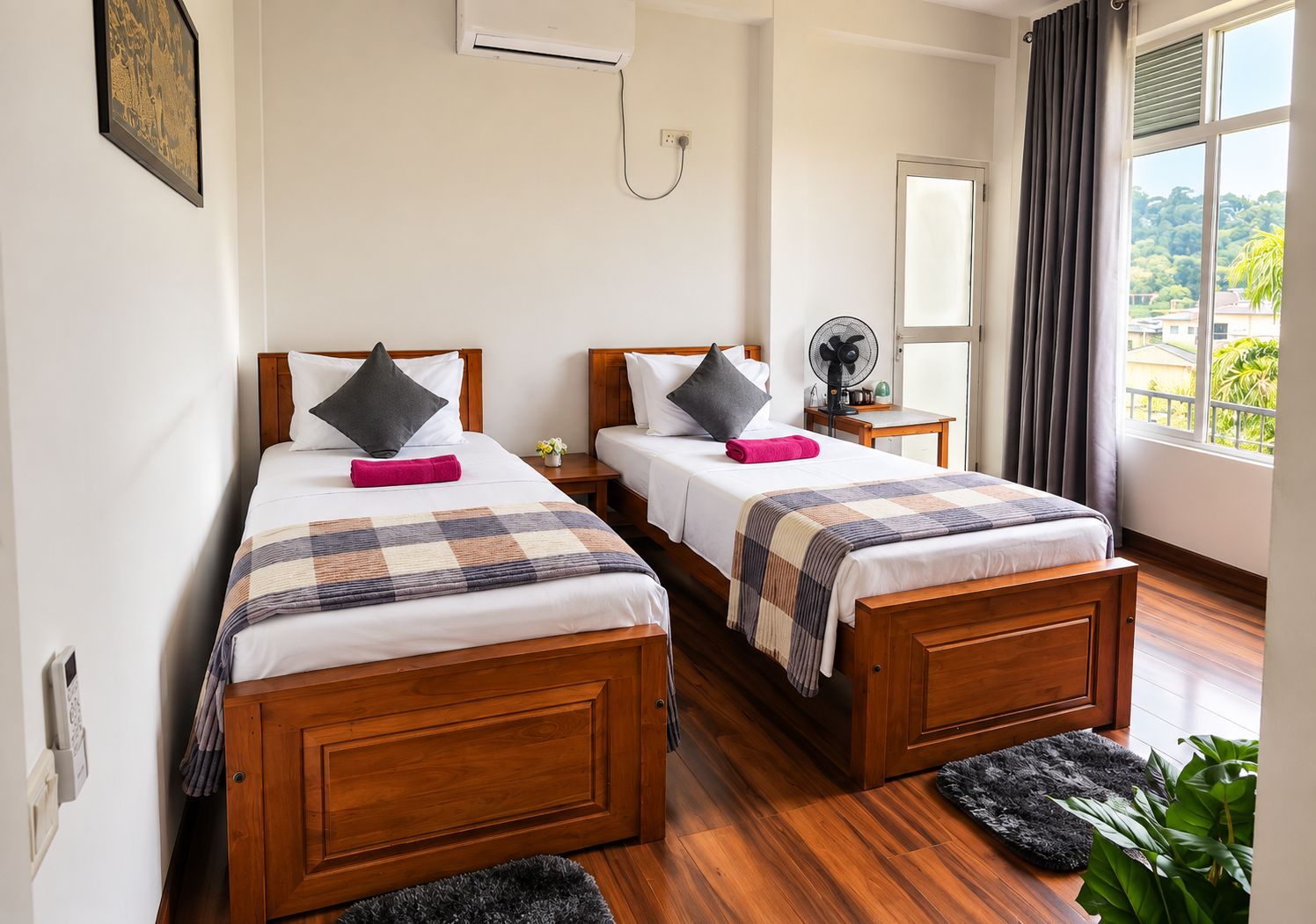 Habitación de hotel con dos camas de madera, una mesita, un ventilador y una ventana con cortinas.
