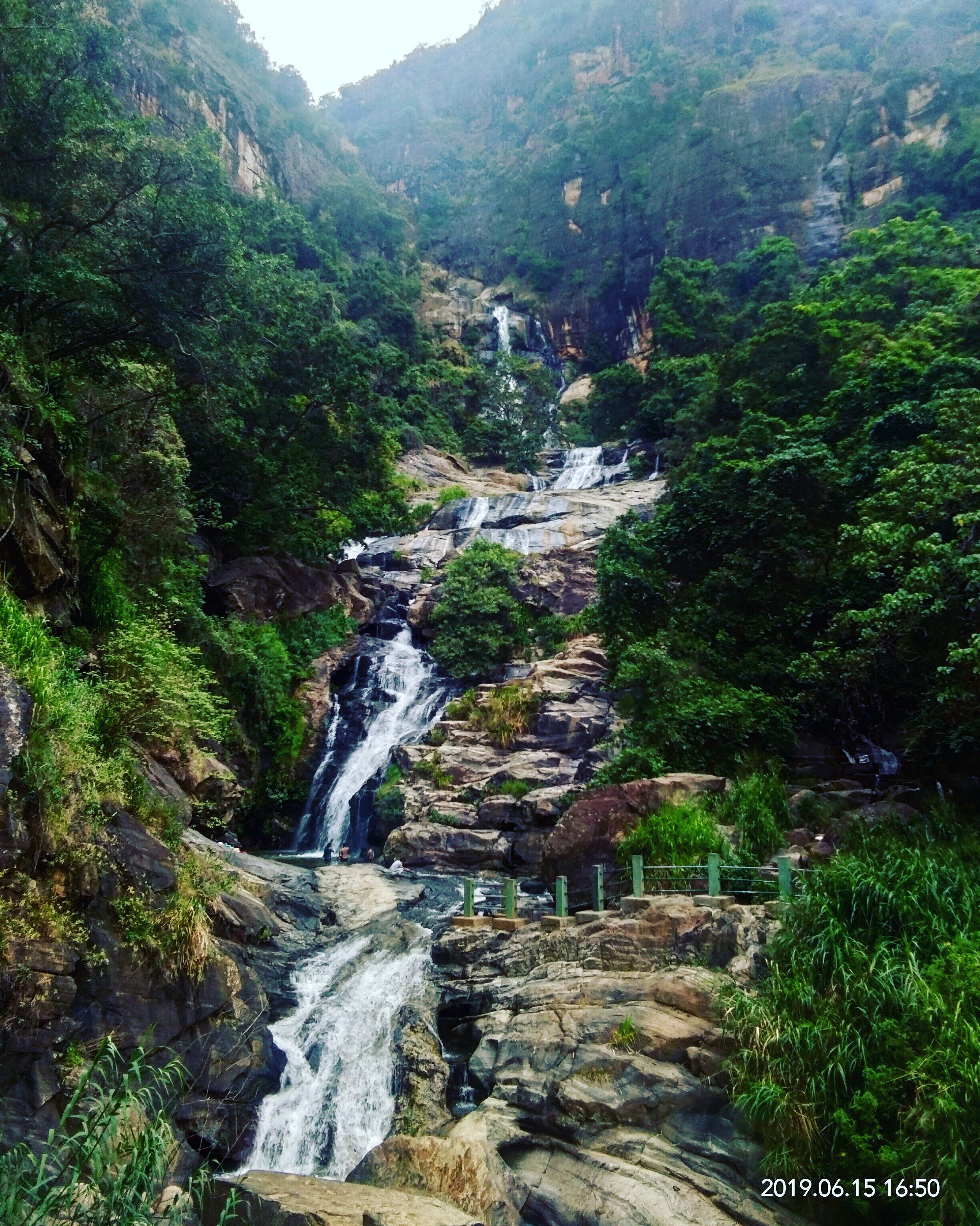 A waterfall cascading down a rocky slope surrounded by lush greenery.