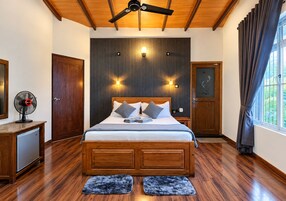 Ein Schlafzimmer mit einem hölzernen Bett, einem Deckenventilator, einer Wandleuchte und einem Fenster mit Vorhängen.