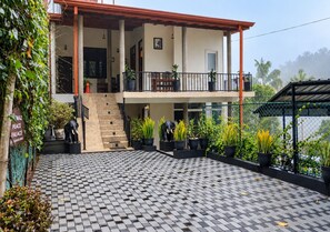 A two-story building with a checkered floor pattern, a balcony with potted plants, and a staircase leading to the upper level. - Poomaz Peace Palace - Ella (Ella)
