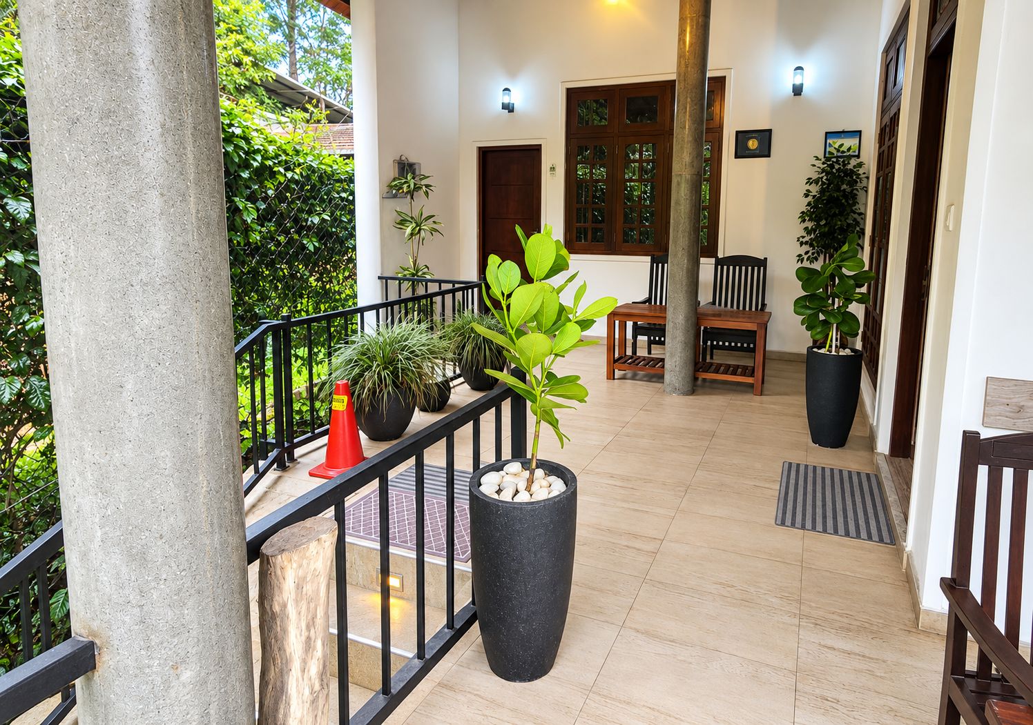 Un espacio al aire libre cubierto con un banco de madera, plantas en macetas y un pilar de piedra.