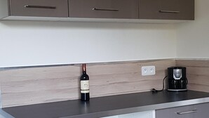 Eine Küche mit grauen Schränken, einer Holzarbeitsplatte, einer Weinflasche und einer Kaffeemaschine.