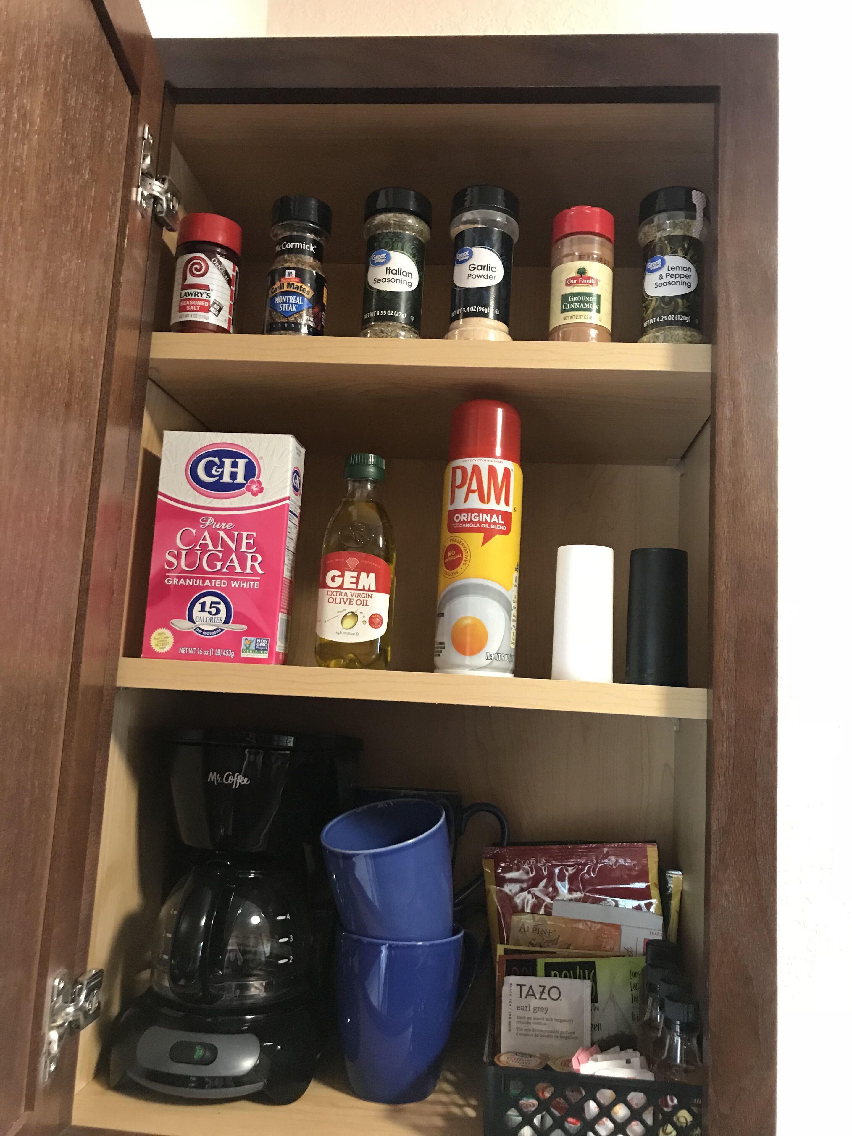 A kitchen cabinet with various food items and kitchen appliances.