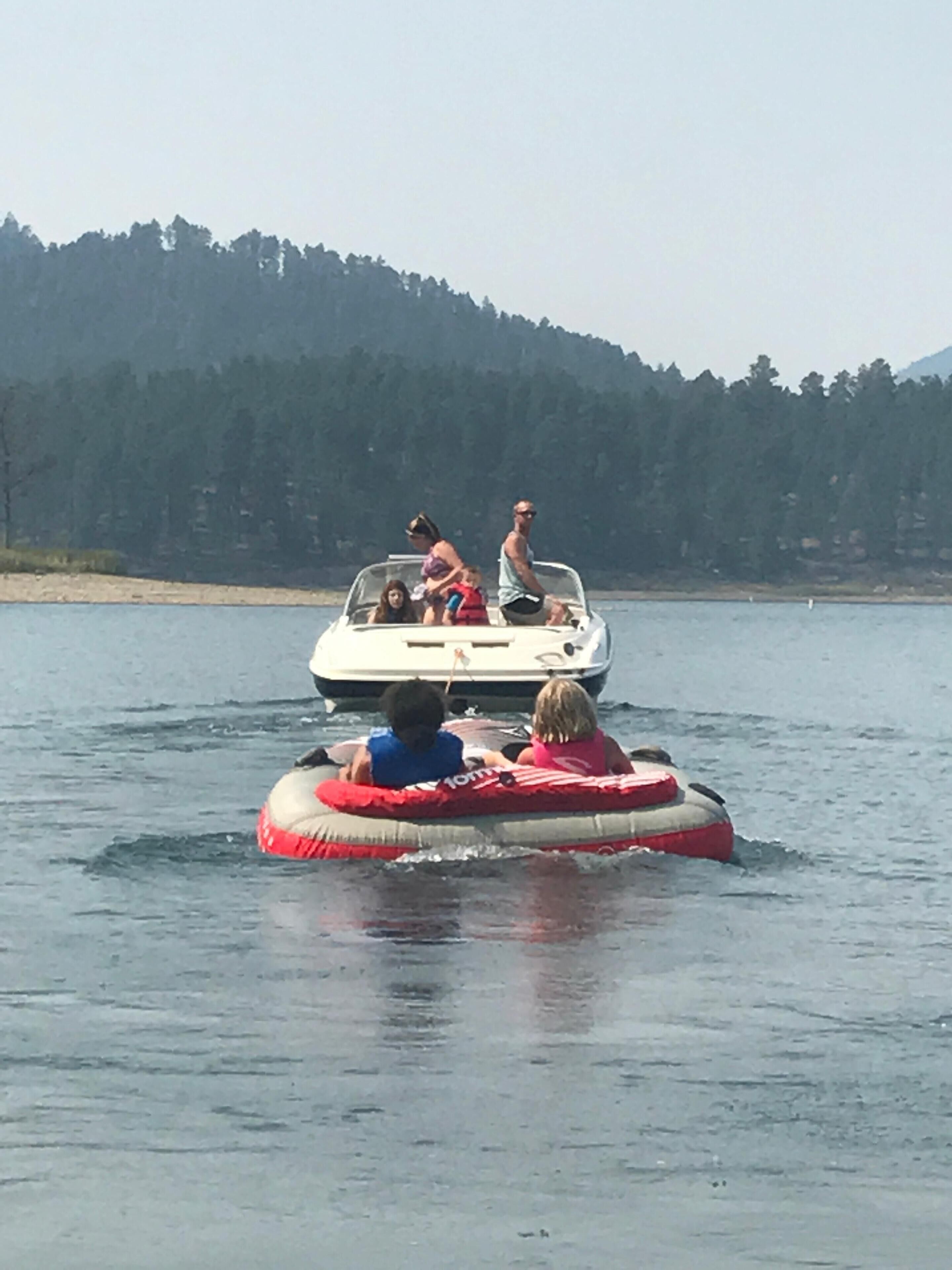 Un bote con gente en un lago, rodeado de árboles.