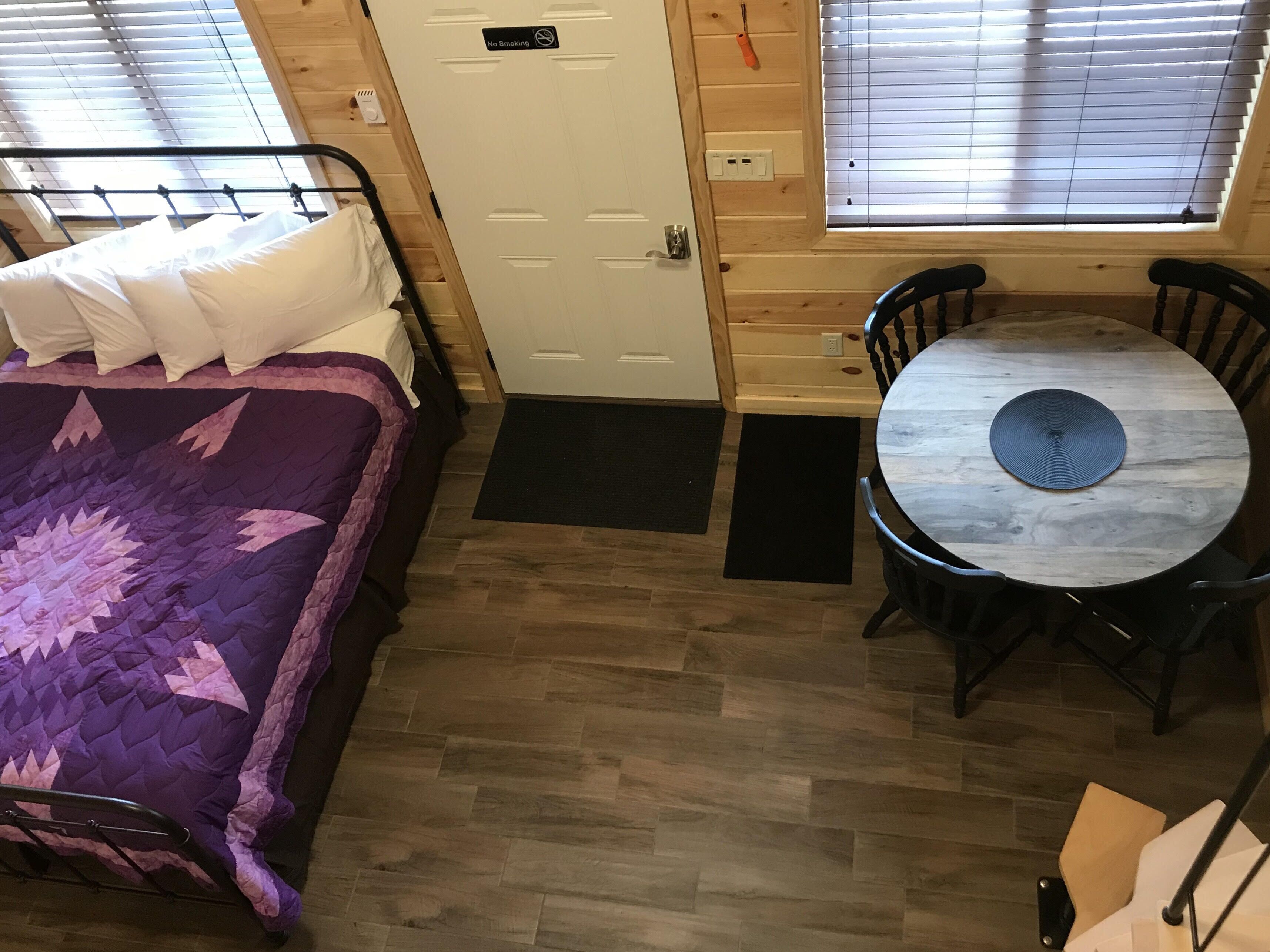 Une petite pièce comprenant un lit, une petite table et deux chaises.