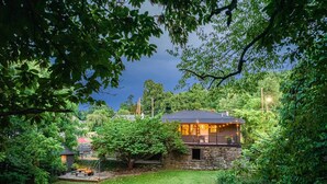 Ein Steinhaus mit Balkon, umgeben von üppigem Grün und einem gepflegten Rasen.