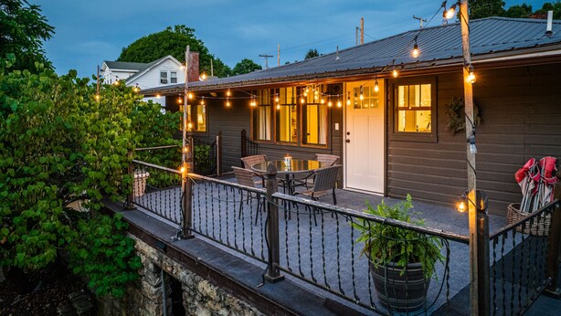 Ein Holzhaus mit Balkon, Lichterketten und einem Tisch mit Stühlen.
