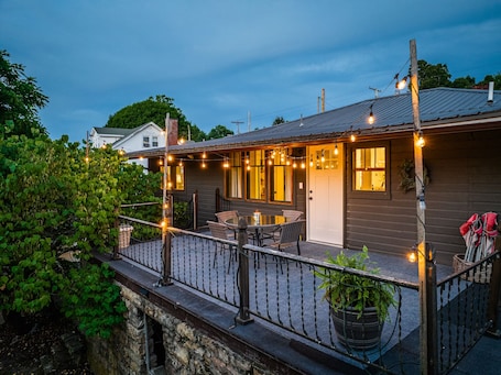 A wooden house with a balcony, string lights, and a table with chairs.